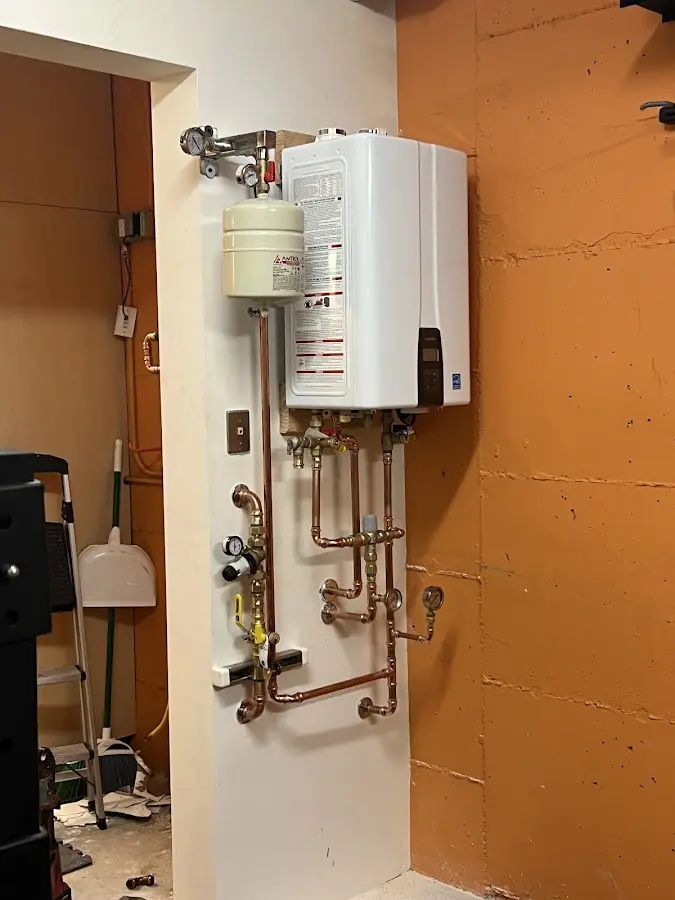 Plumbing technician inspecting water heater connections in New Baltimore